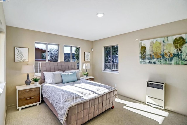 bedroom with heating unit and light colored carpet