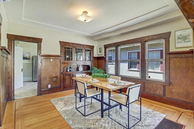 dining space featuring wood walls and light wood-type flooring