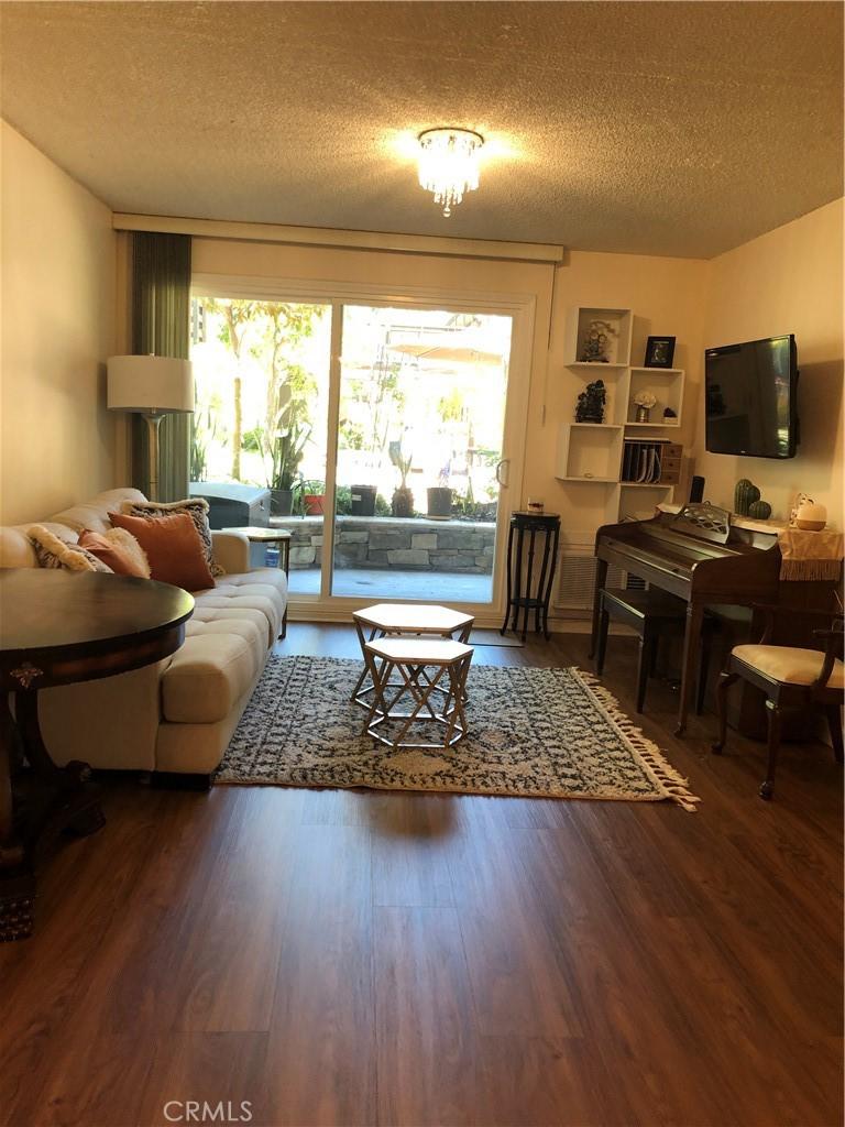 living room with a textured ceiling and dark hardwood / wood-style flooring