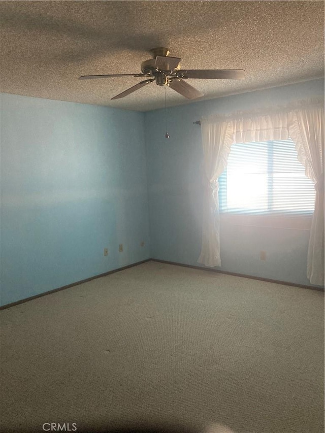 carpeted spare room featuring ceiling fan and a textured ceiling