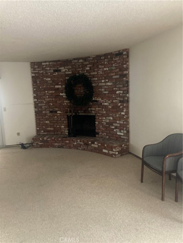 living room with a brick fireplace, carpet, and a textured ceiling