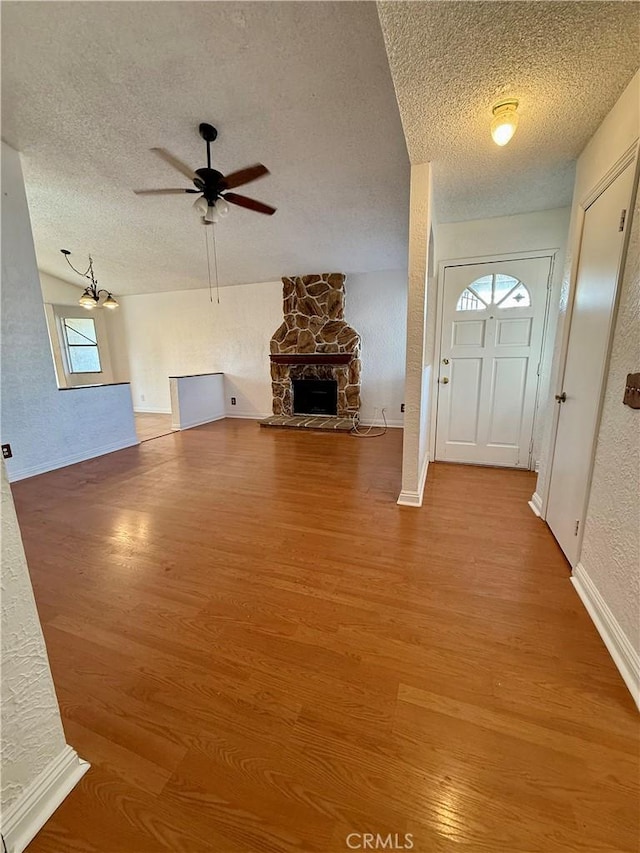 entryway with hardwood / wood-style flooring, a textured ceiling, ceiling fan, and a fireplace