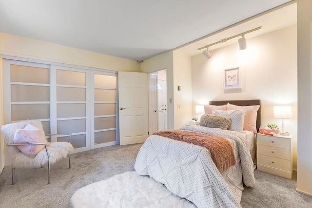 bedroom featuring track lighting and light colored carpet