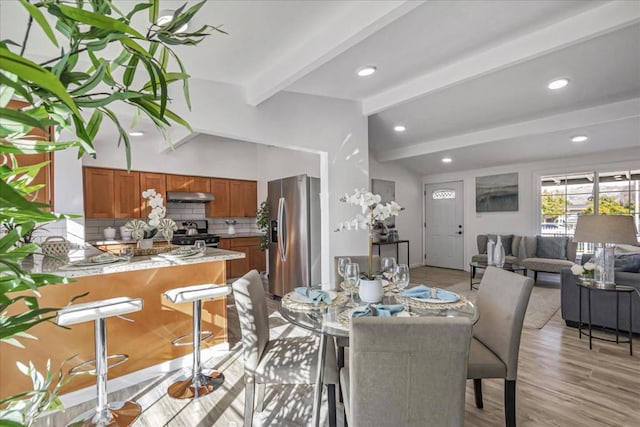 dining space featuring beamed ceiling and light hardwood / wood-style floors