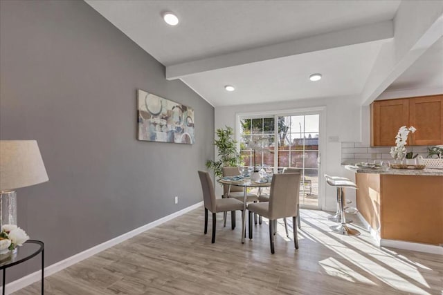 dining space featuring light hardwood / wood-style floors and lofted ceiling with beams