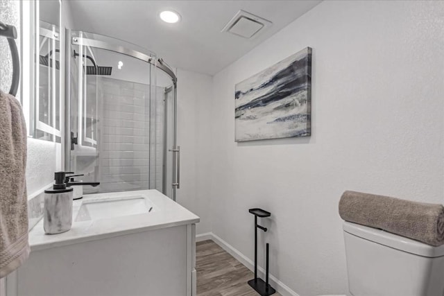 bathroom with vanity, hardwood / wood-style flooring, a shower with door, and toilet