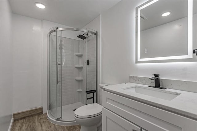 bathroom with hardwood / wood-style flooring, vanity, toilet, and a shower with shower door