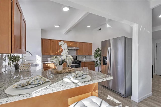 kitchen featuring beamed ceiling, sink, a kitchen breakfast bar, kitchen peninsula, and stainless steel refrigerator with ice dispenser