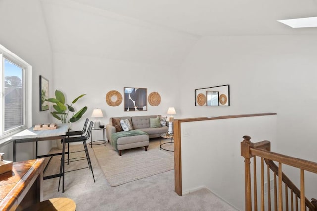 carpeted living room featuring high vaulted ceiling and a skylight