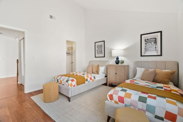 bedroom with light hardwood / wood-style flooring and high vaulted ceiling