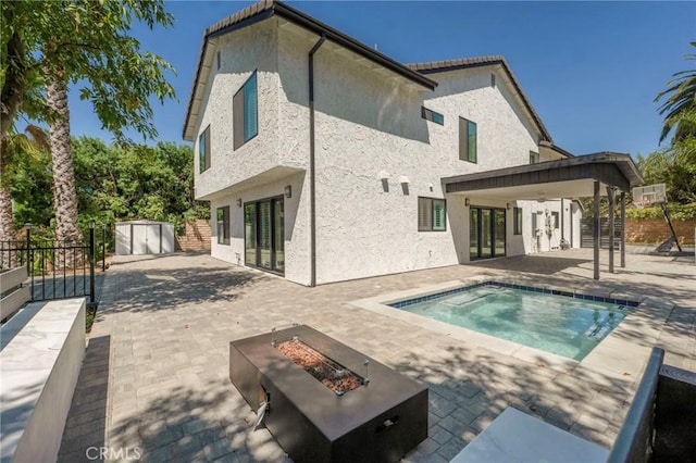 rear view of house featuring a storage shed, a patio, and a fire pit