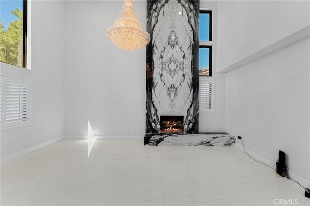 living room featuring an inviting chandelier, a high end fireplace, and a high ceiling