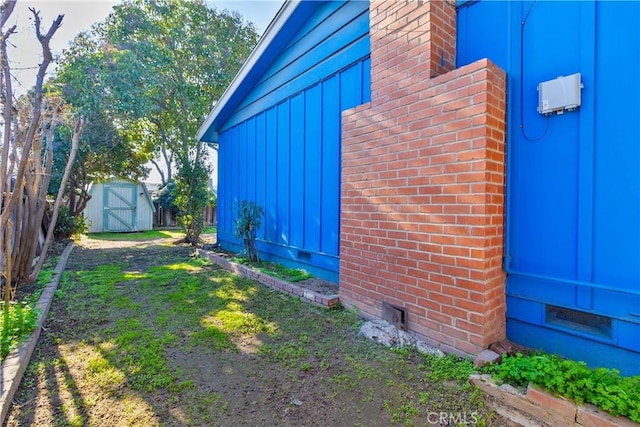 view of side of property featuring a lawn and a storage unit