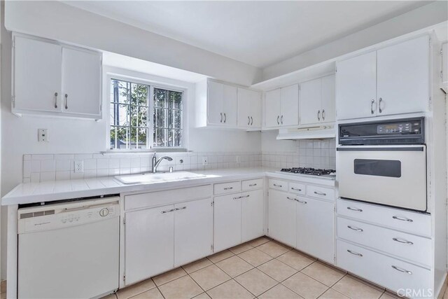 kitchen featuring light tile patterned floors, white cabinetry, sink, and white appliances