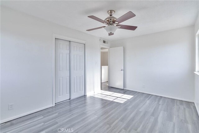 unfurnished bedroom with light wood-type flooring, a closet, and ceiling fan