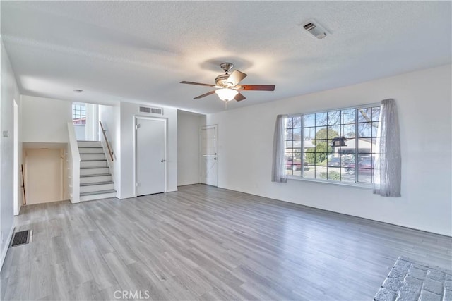 unfurnished living room with ceiling fan, a healthy amount of sunlight, a textured ceiling, and light hardwood / wood-style flooring