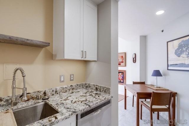 kitchen featuring dishwasher, sink, light stone counters, and white cabinetry