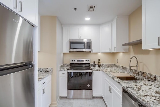 kitchen featuring light stone countertops, appliances with stainless steel finishes, white cabinetry, and sink