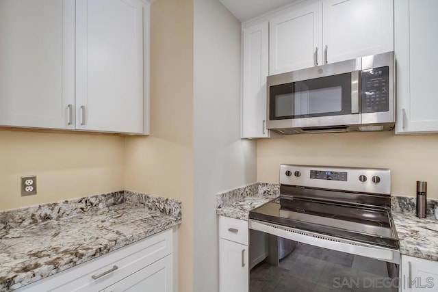 kitchen featuring light stone countertops, stainless steel appliances, and white cabinetry