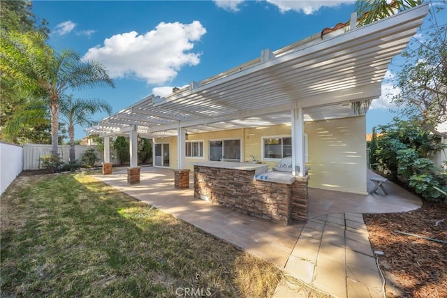 back of house featuring a lawn, a pergola, a patio, and exterior bar