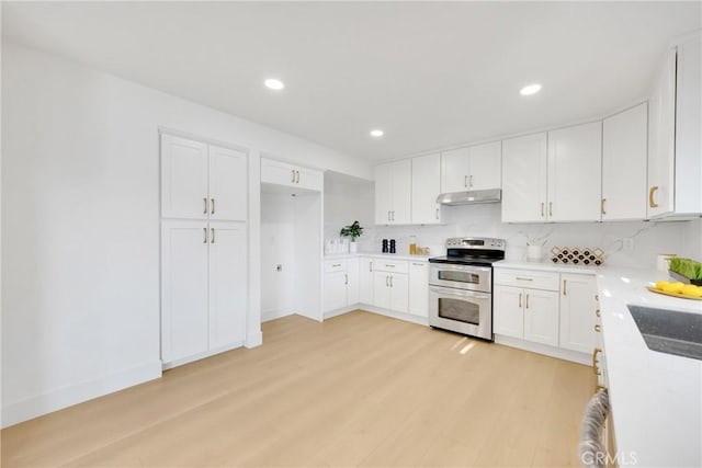 kitchen featuring sink, light hardwood / wood-style flooring, tasteful backsplash, white cabinets, and range with two ovens