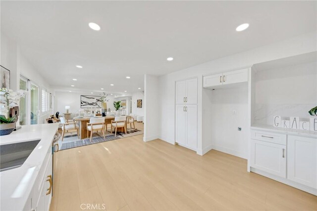 kitchen with sink, white cabinets, and light hardwood / wood-style flooring