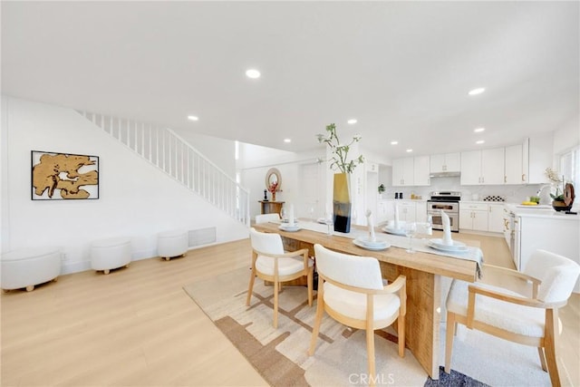 kitchen featuring tasteful backsplash, white cabinets, double oven range, and light hardwood / wood-style flooring