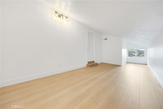 additional living space with lofted ceiling and light wood-type flooring