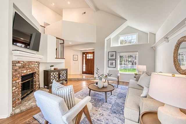 living room with a brick fireplace, hardwood / wood-style flooring, and vaulted ceiling with beams