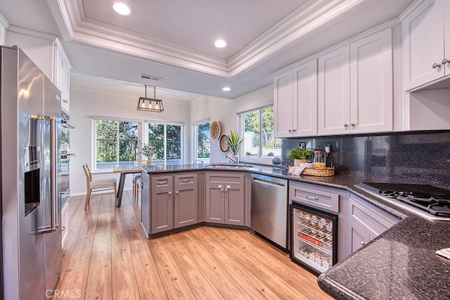 kitchen featuring a raised ceiling, white cabinets, and stainless steel appliances