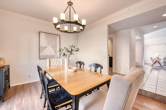 dining space featuring light wood-type flooring, a notable chandelier, and crown molding