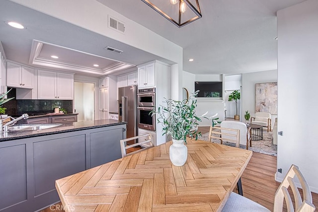 dining area featuring ornamental molding, a raised ceiling, and sink