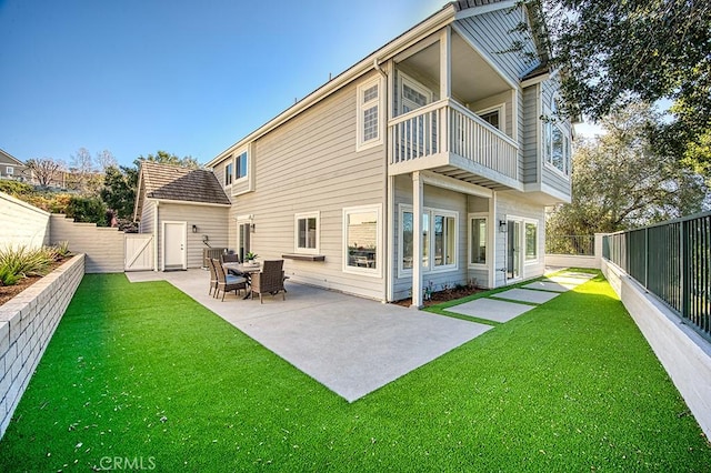 back of property featuring a yard, a balcony, and a patio