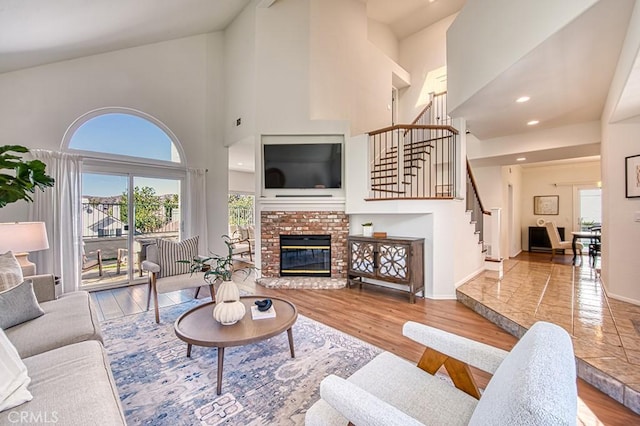 living room featuring a fireplace, a towering ceiling, and light hardwood / wood-style flooring