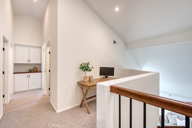 hall with light colored carpet and high vaulted ceiling