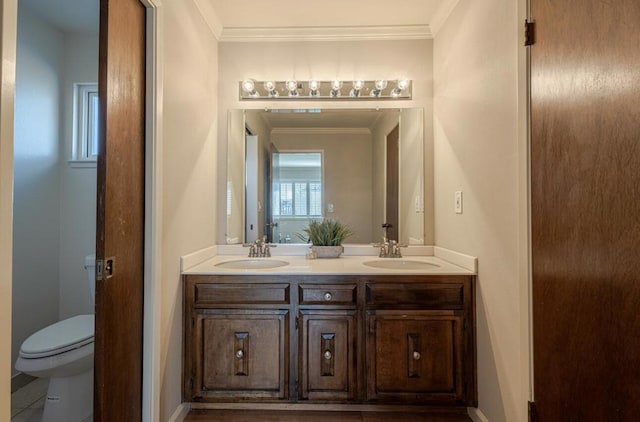 bathroom with toilet, vanity, and ornamental molding