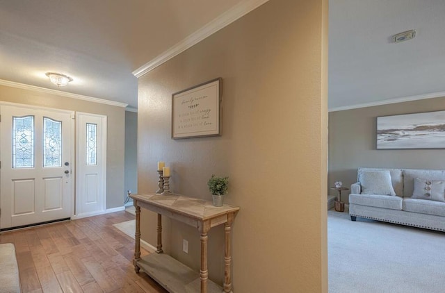 foyer entrance with ornamental molding and light hardwood / wood-style flooring