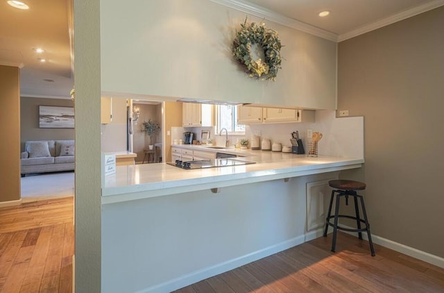 kitchen with light wood-type flooring, a kitchen bar, kitchen peninsula, and sink