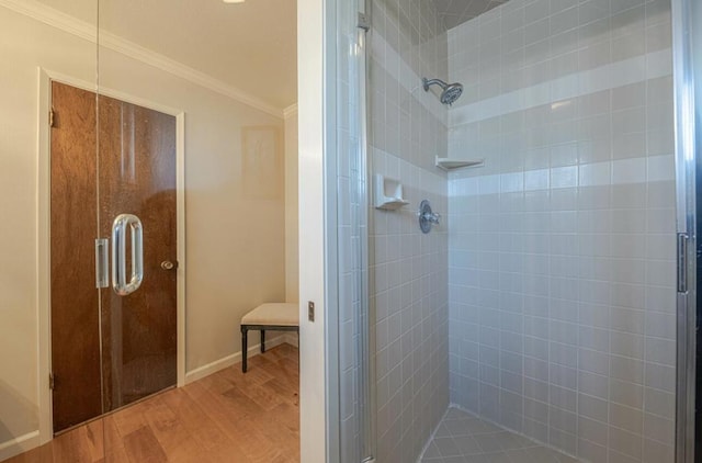 bathroom with hardwood / wood-style flooring, a shower with shower door, and crown molding