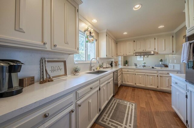 kitchen featuring hardwood / wood-style floors, white cabinetry, sink, stainless steel dishwasher, and crown molding