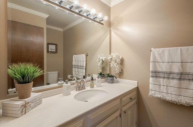 bathroom featuring toilet, vanity, and ornamental molding