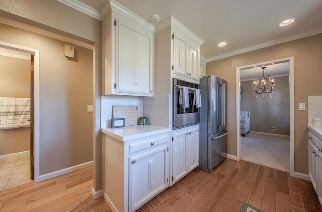 kitchen with appliances with stainless steel finishes, white cabinets, ornamental molding, a chandelier, and light hardwood / wood-style flooring