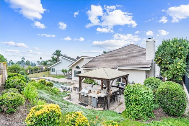 rear view of property with area for grilling, a gazebo, and a patio