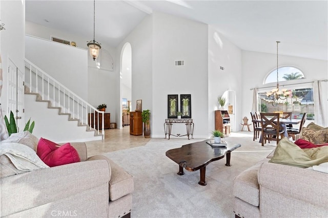 living room with a notable chandelier, light colored carpet, and high vaulted ceiling