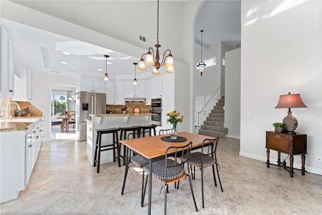 dining room with light tile patterned flooring, a tray ceiling, and sink