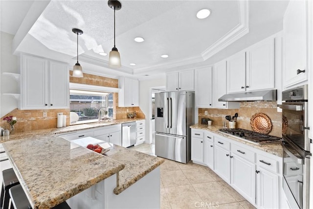 kitchen featuring stainless steel appliances, a tray ceiling, ornamental molding, white cabinets, and decorative light fixtures