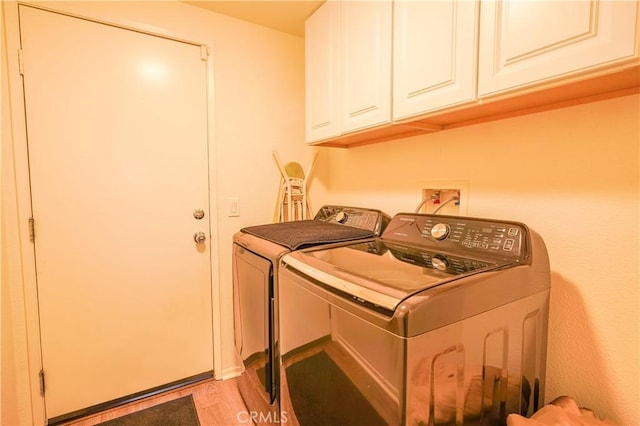 laundry room with light hardwood / wood-style floors, cabinets, and washer and clothes dryer