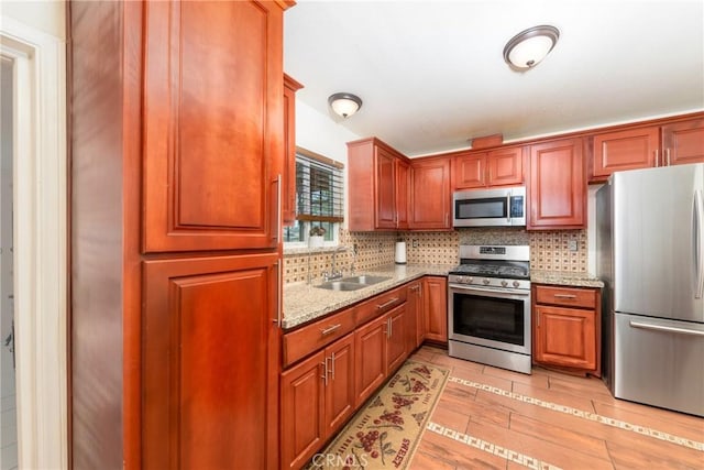 kitchen with light stone countertops, stainless steel appliances, sink, backsplash, and light tile patterned floors