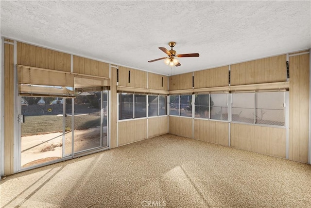 spare room featuring a textured ceiling, carpet, and wood walls