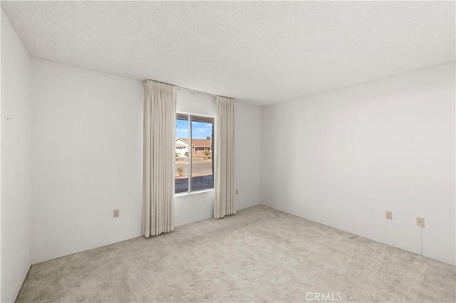 empty room with light colored carpet and a textured ceiling